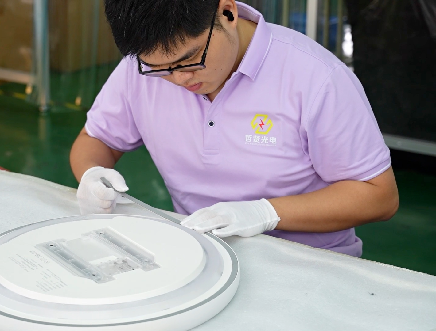 Actual Zhexian employee assembling a ceiling light, wearing the company's original logo uniform